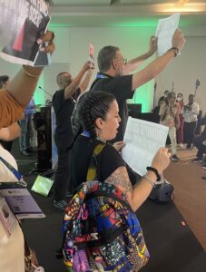 Protesters on stage at the AIDS 2026 conference, in profile.