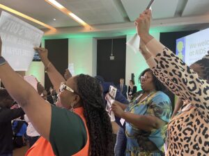Protesters on stage at the AIDS 2026 conference, in profile.